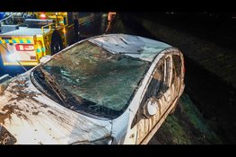 Auto ondersteboven in sloot op spiegelgladde weg, bestuurster met spoed naar ziekenhuis